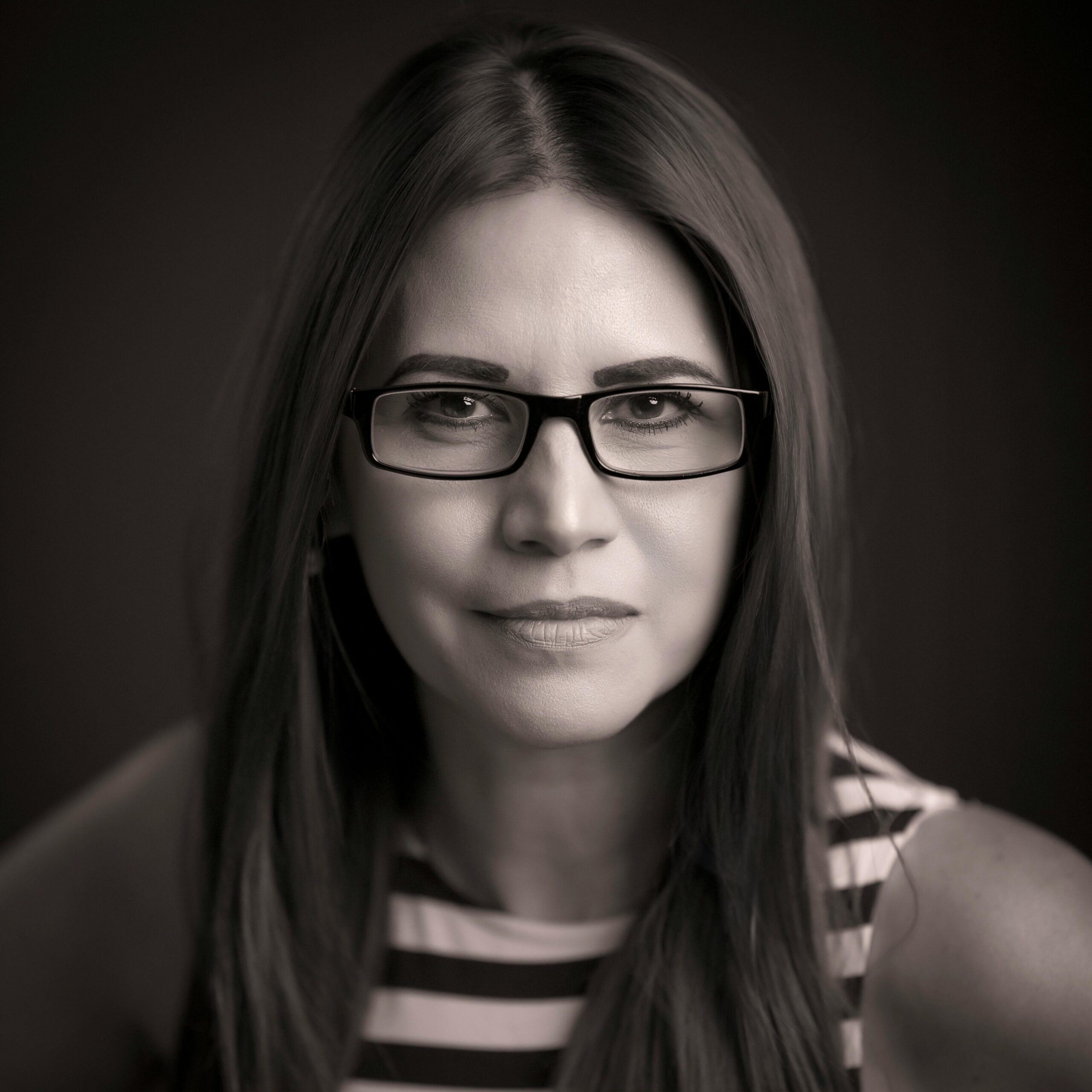Portrait of a professional woman with glasses, emphasizing a confident and intelligent expression.